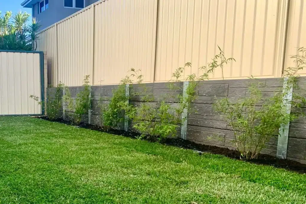 Concrete sleeper retaining wall with boundary fencing in Melbourne